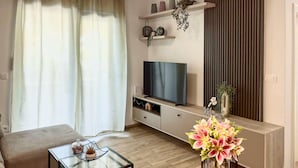 A modern living room with a flat-screen TV, a glass coffee table, a sofa, and a decorative vase with flowers. - Lovely apartment in Blace with WiFi (Blace)