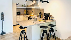 A modern kitchen with a central island, bar stools, a microwave, a coffee machine, and a hanging light fixture. - Lovely apartment in Blace with WiFi (Blace)