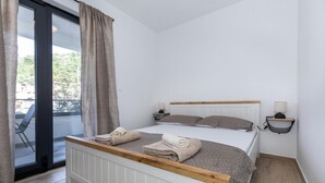 A bedroom with a bed, two bedside tables, a window with curtains, and a view of greenery outside. - Lovely apartment in Blace with WiFi (Blace)