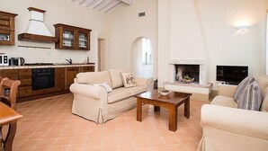 A spacious living area with a fireplace, a kitchen with wooden cabinets, and a dining area with a table and chairs.