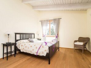 Una camera da letto con un letto di legno, un comodino, una sedia e una finestra con tende.