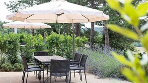 An outdoor patio with a table and chairs, surrounded by lush greenery and trees. - Casa Dracena L: A welcoming two-story apartment situated in the heart of the Tuscan countryside, with Free WI-FI. (Trequanda)