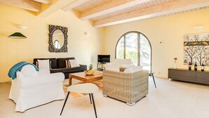 A spacious living room with a high ceiling, a large arched window, and a modern fireplace. - Casa Dracena L: A welcoming two-story apartment situated in the heart of the Tuscan countryside, with Free WI-FI. (Trequanda)