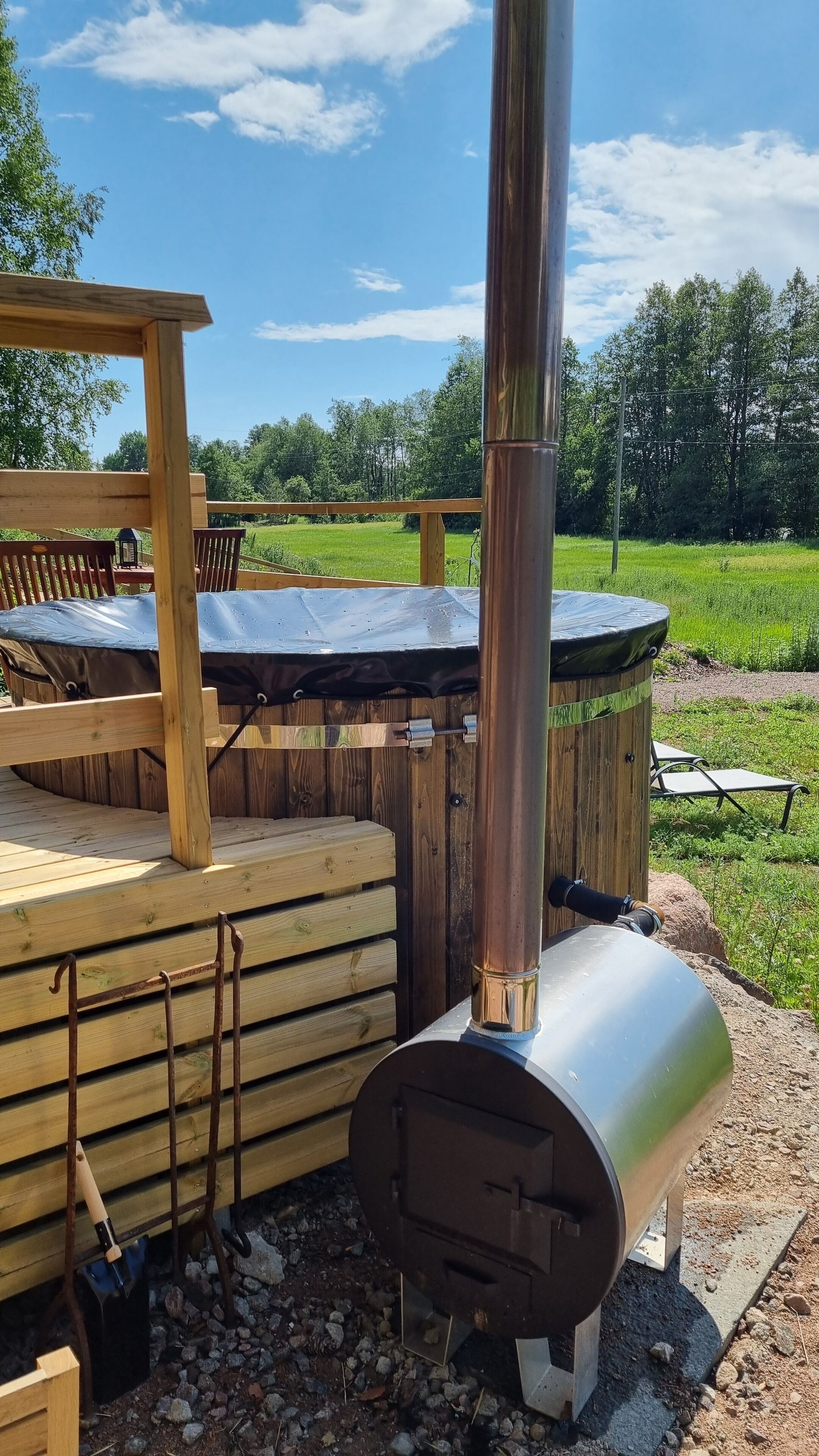 Un espace extérieur aménagé dans un style rustique, avec un poêle en métal, des bancs en bois et une table de pique-nique.