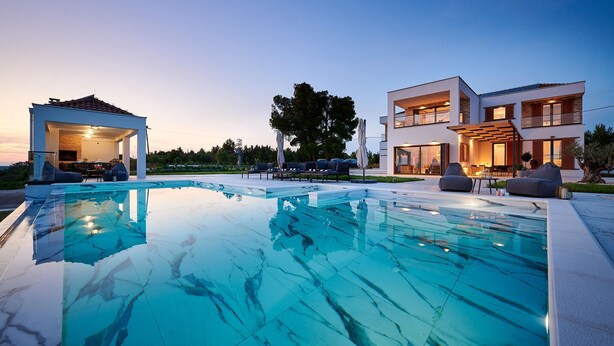 Ein moderner Poolbereich mit klarem Pool, Liegestühlen und einer überdachten Sitzgelegenheit.