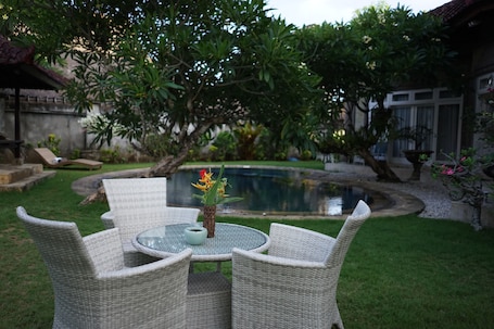 Una piscina al aire libre, sombrillas, sillones reclinables de piscina