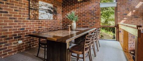 A dining area with a brick wall, a wooden ceiling, and a large window.