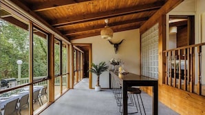 A spacious room with large windows, a wooden ceiling, a dining table with chairs, and a bull's head mounted on the wall. - Seednest Treehouse | Forest & Mountain View (Sassafras)