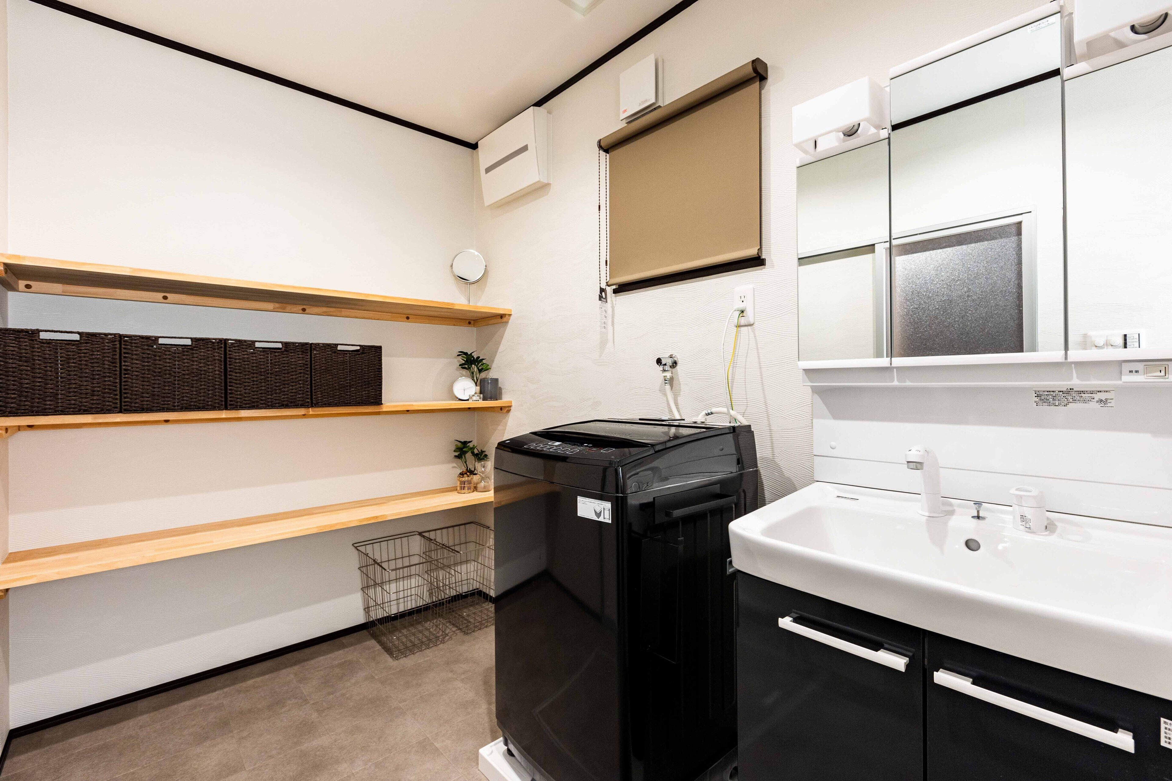 A compact kitchen with a built-in washing machine, a sink, and wooden shelves.
