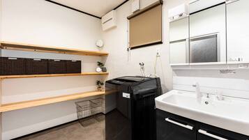 A compact kitchen with a built-in washing machine, a sink, and wooden shelves.