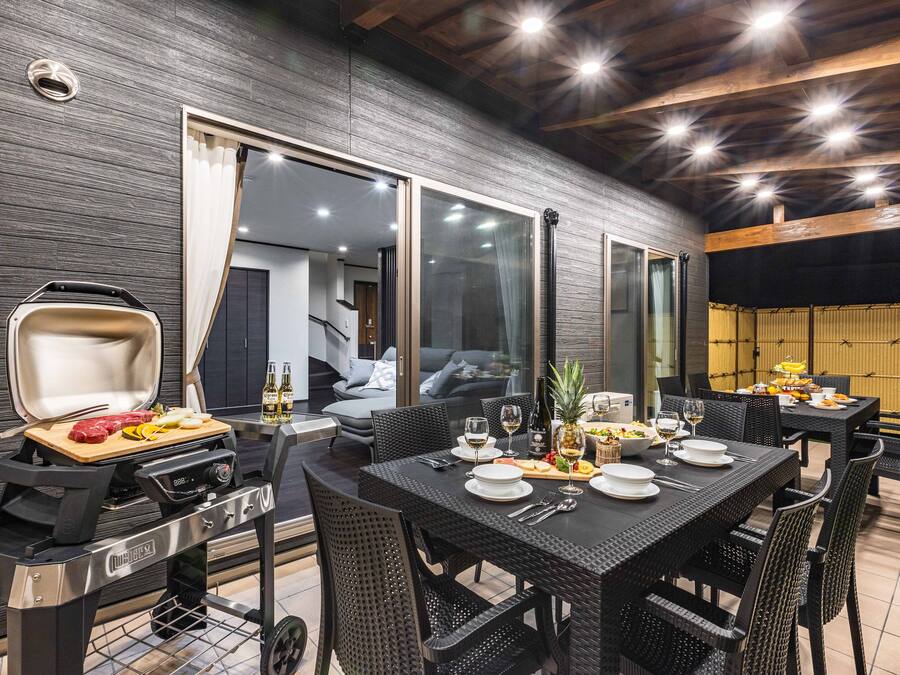 Zona d'exterior per a dinar amb una barbacoa, taula, caires i vistes cap a l'interior.