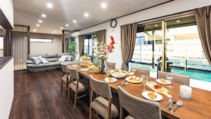 A dining area with a wooden table set for a meal, surrounded by chairs, with a view of a swimming pool and a balcony.