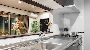 A modern kitchen with stainless steel appliances, a double sink, and a window with curtains.
