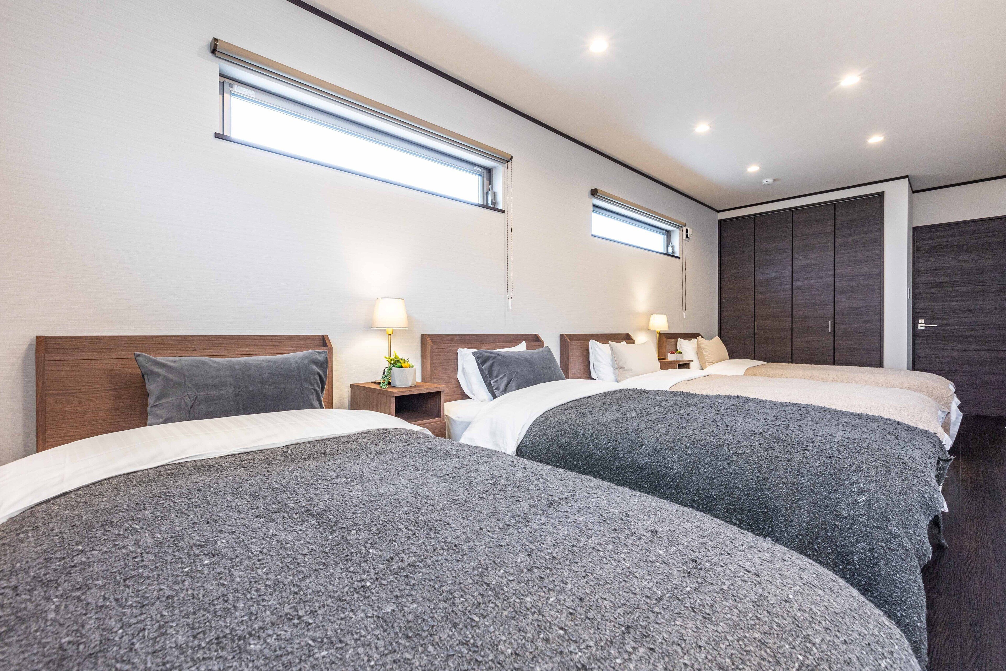 A hotel room with two beds, a wardrobe, and a window.