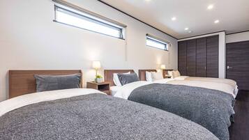 A hotel room with two beds, a wardrobe, and a window.