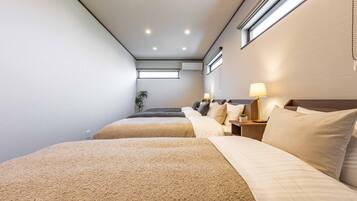 Habitación de hotel con dos camas, una ventana, una planta y una mesita de noche con lámpara.