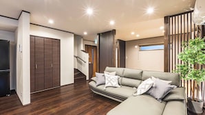 A modern living room with a sectional sofa, a potted plant, and a wooden floor.
