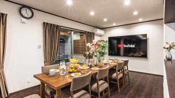A modern dining area with a wooden table set for a meal, a clock, and a YouTube logo on the wall.