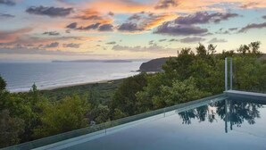 Una piscina con vista al océano y al atardecer.