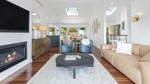 Una sala de estar moderna con chimenea, sofá, mesa de centro y un comedor con sillas.