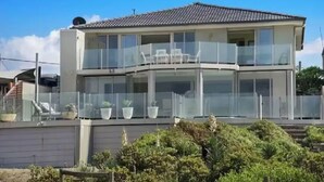 A two-story house with a balcony, potted plants, and a clear sky. - Luxury Villas Ocean View on the Esplanade (Walk to the beach) (Central Coast)