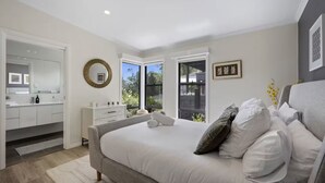 A bedroom with a bed, a dresser, a mirror, and a window. - Luxury Villas Araluen Waterfront Getaway (Walk to the beach) (Central Coast)