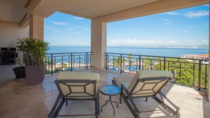 Ein Balkon mit zwei Stühlen und einem kleinen Tisch mit Blick auf einen Strand und den Ozean.