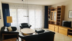 A living room with a sofa, two armchairs, a coffee table, a TV, and a bookshelf. - Edelweiss A by Interhome (Leukerbad)