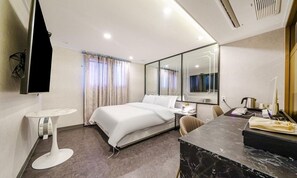 Une chambre d’hôtel moderne dotée d’un grand lit, d’un bureau avec un ordinateur, d’un miroir et d’une salle de bain avec des toilettes et un lavabo.