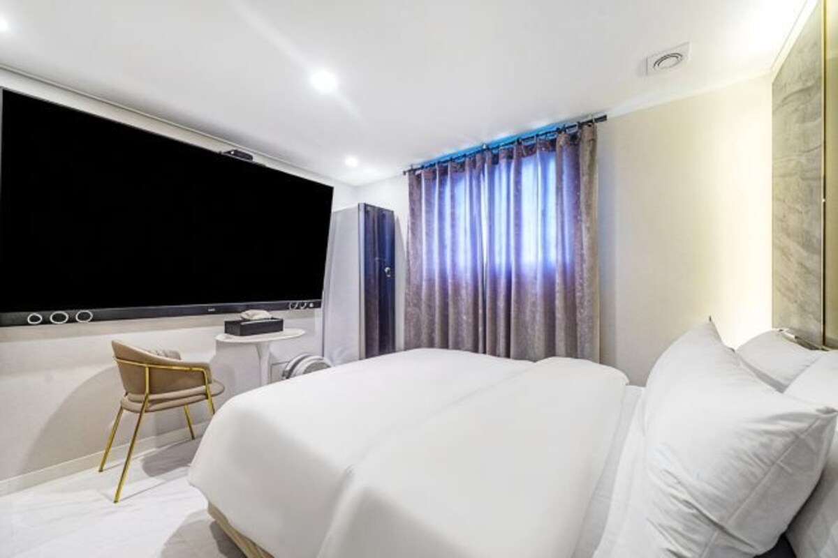 Una habitación de hotel con una cama grande, un escritorio, una silla y un televisor.