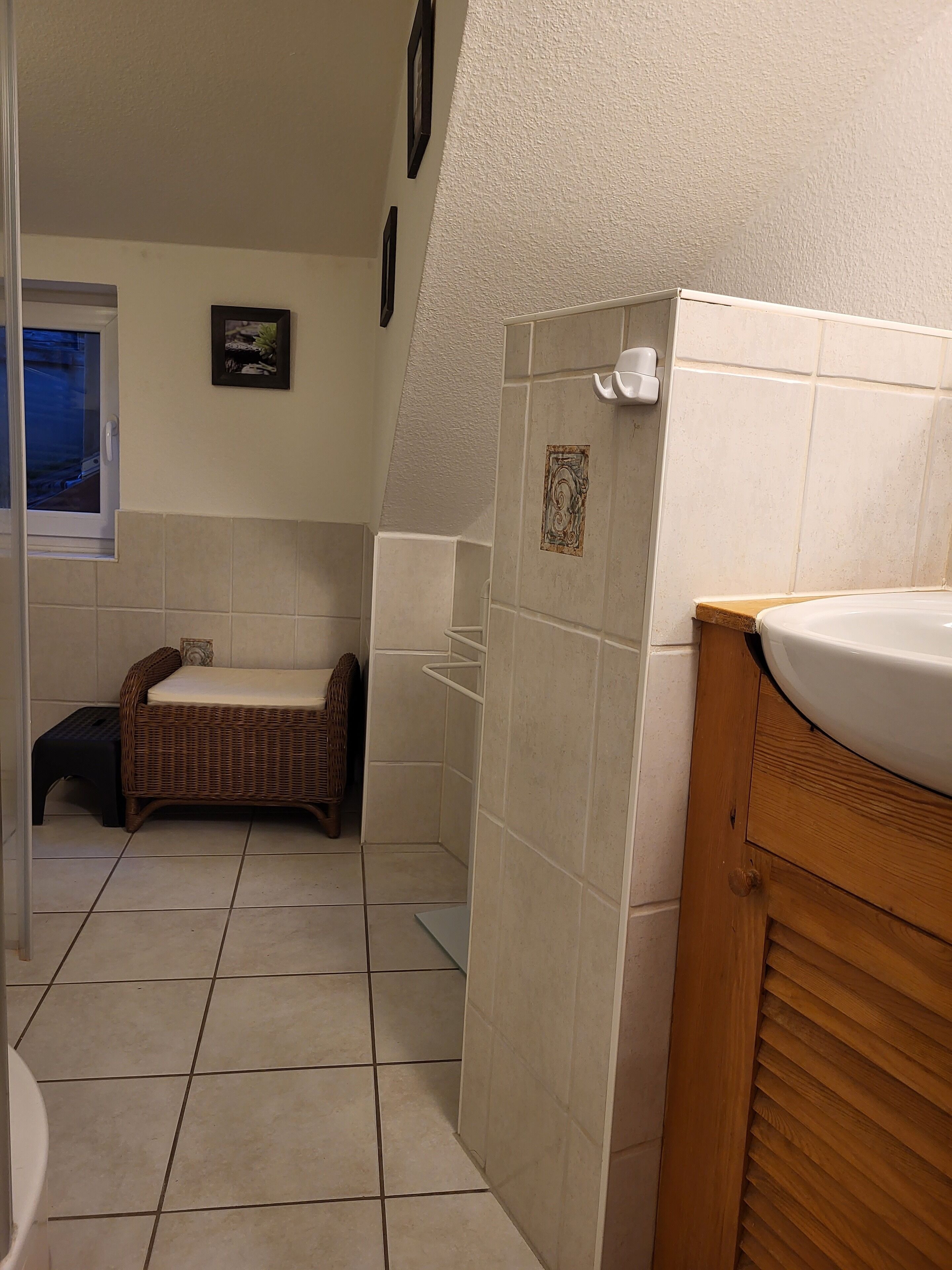 A bathroom with a bathtub, a wooden vanity, and a small wicker bench.