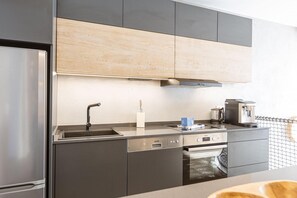 Une cuisine moderne équipée d’un réfrigérateur en acier inoxydable, d’un lave-vaisselle, d’un four et d’une machine à café.