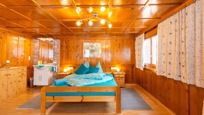 Ein Holzblockhaus-Innenraum mit Bett, Bad und Küchenzeile.
