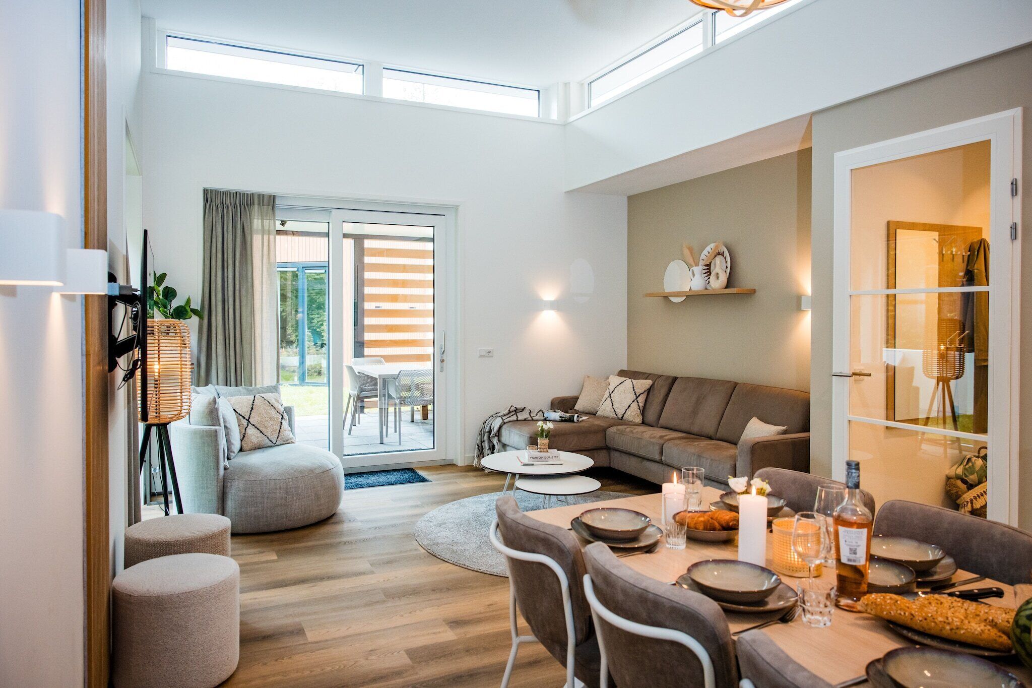 Una sala de estar moderna con sofá, reposapiés y una mesa de comedor dispuesta para una comida.