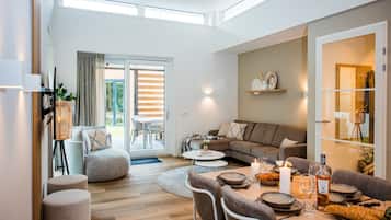 Una sala de estar moderna con sofá, reposapiés y una mesa de comedor dispuesta para una comida.