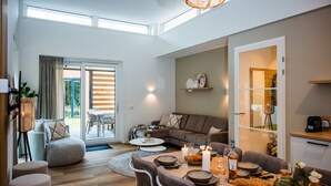 Een moderne woonkamer met een eethoek, met een bank, salontafel en een eettafel gedekt voor vier personen.