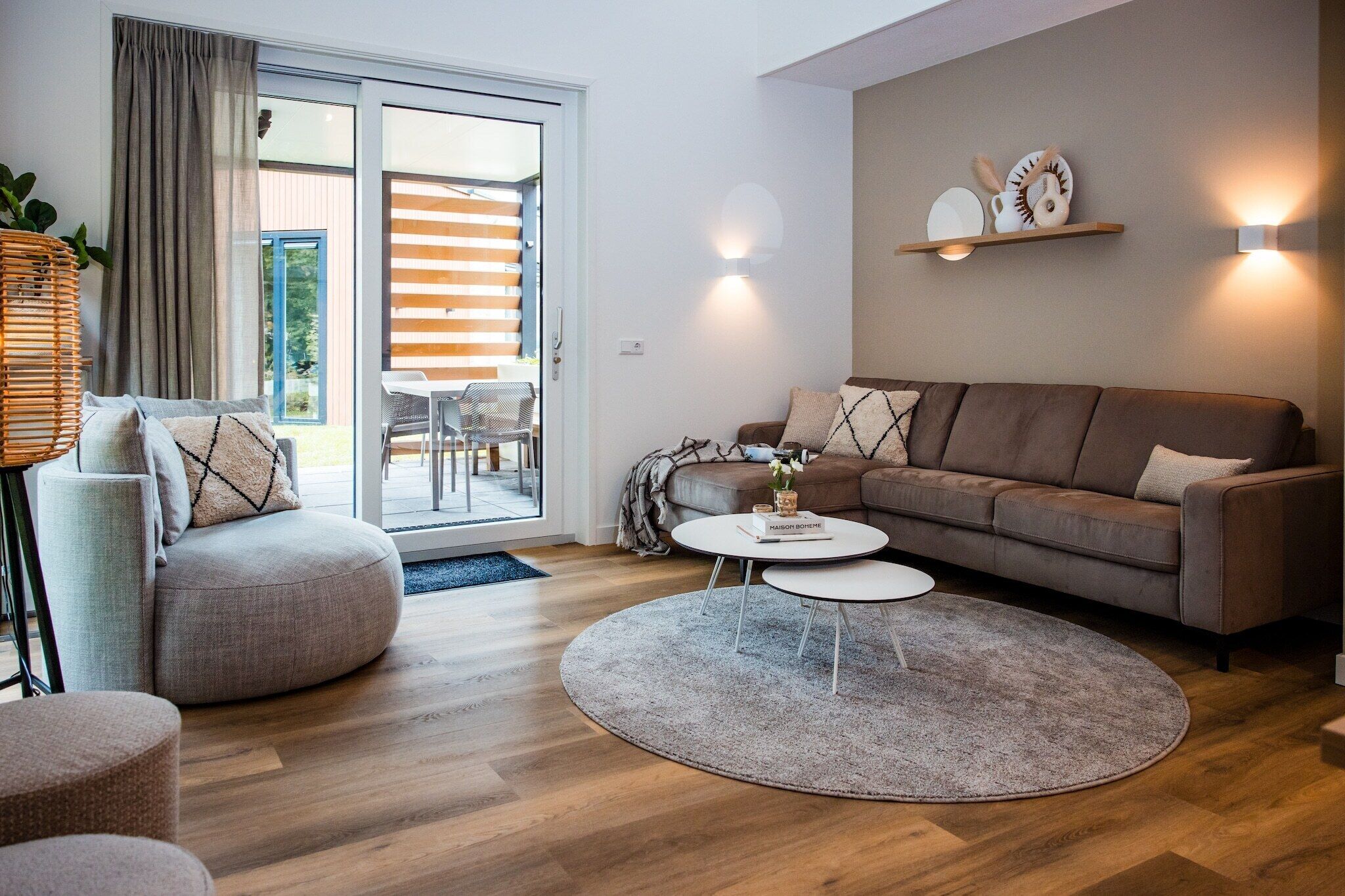 A modern living room with a sofa, two side tables, a coffee table, and a wicker chair.