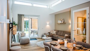 Een moderne woonkamer met een bank, voetenbankje en een eettafel gedekt voor een maaltijd.
