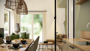 A modern kitchen with a wooden countertop, a sink, and a dining area with a table set for two. - Chalet in Veluwe with Peaceful Surroundings (Voorthuizen)