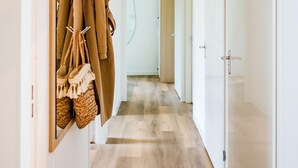 A hallway with wooden flooring, a coat rack with hanging items, and a door on the right. - Beautiful holiday home in Voorthuizen (Voorthuizen)