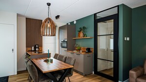 A modern kitchen with a wooden dining table, grey cabinets, and a black-framed sliding door. - Beautiful holiday home in Voorthuizen (Voorthuizen)