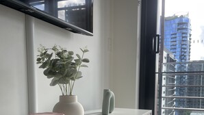 En moderne stue med et hvidt konsolbord, en potteplante, en lyserød beholder og et tastatur.