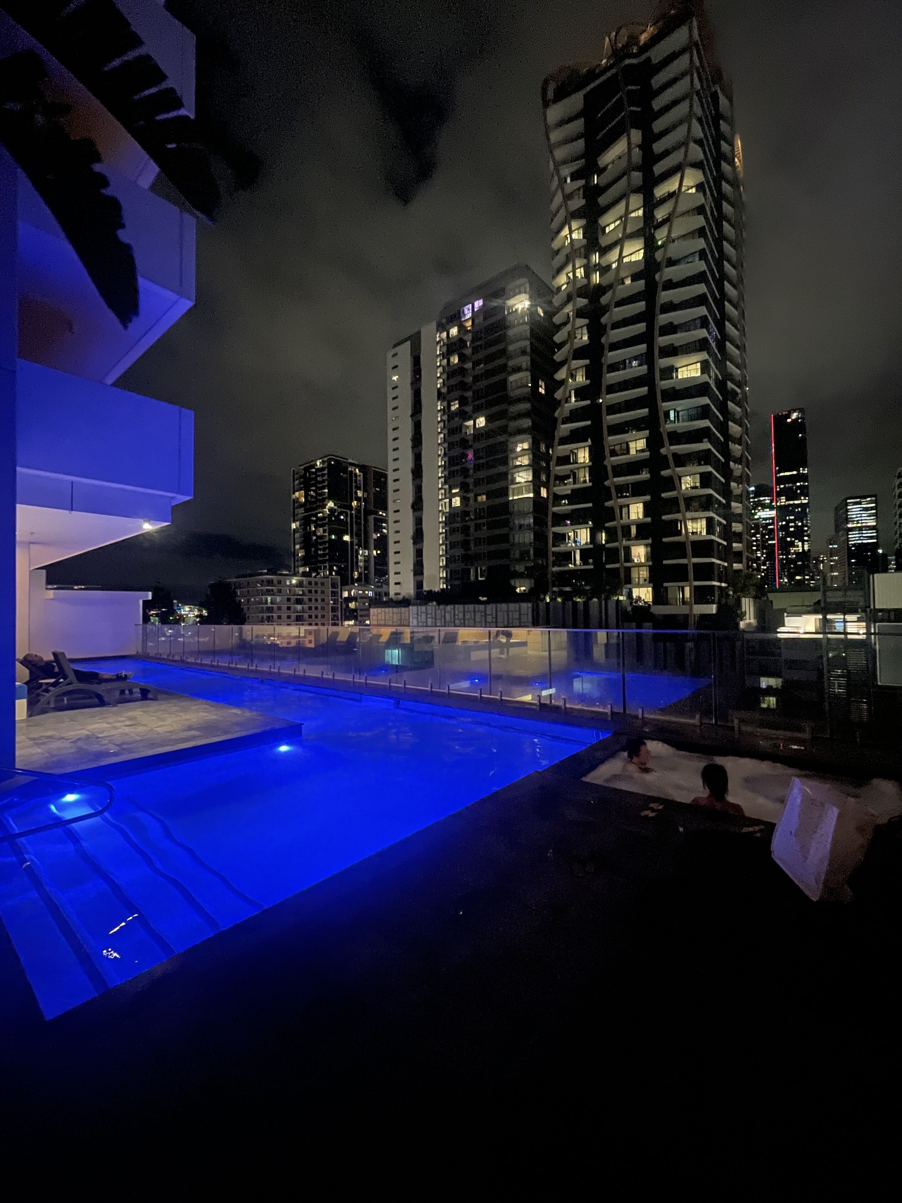 Una piscina sul tetto con vista su grattacieli di notte.