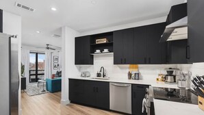 A modern kitchen with black cabinets, a white countertop, and a built-in dishwasher.