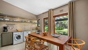 Una cucina moderna con zona pranzo, lavatrice e vista su un giardino.