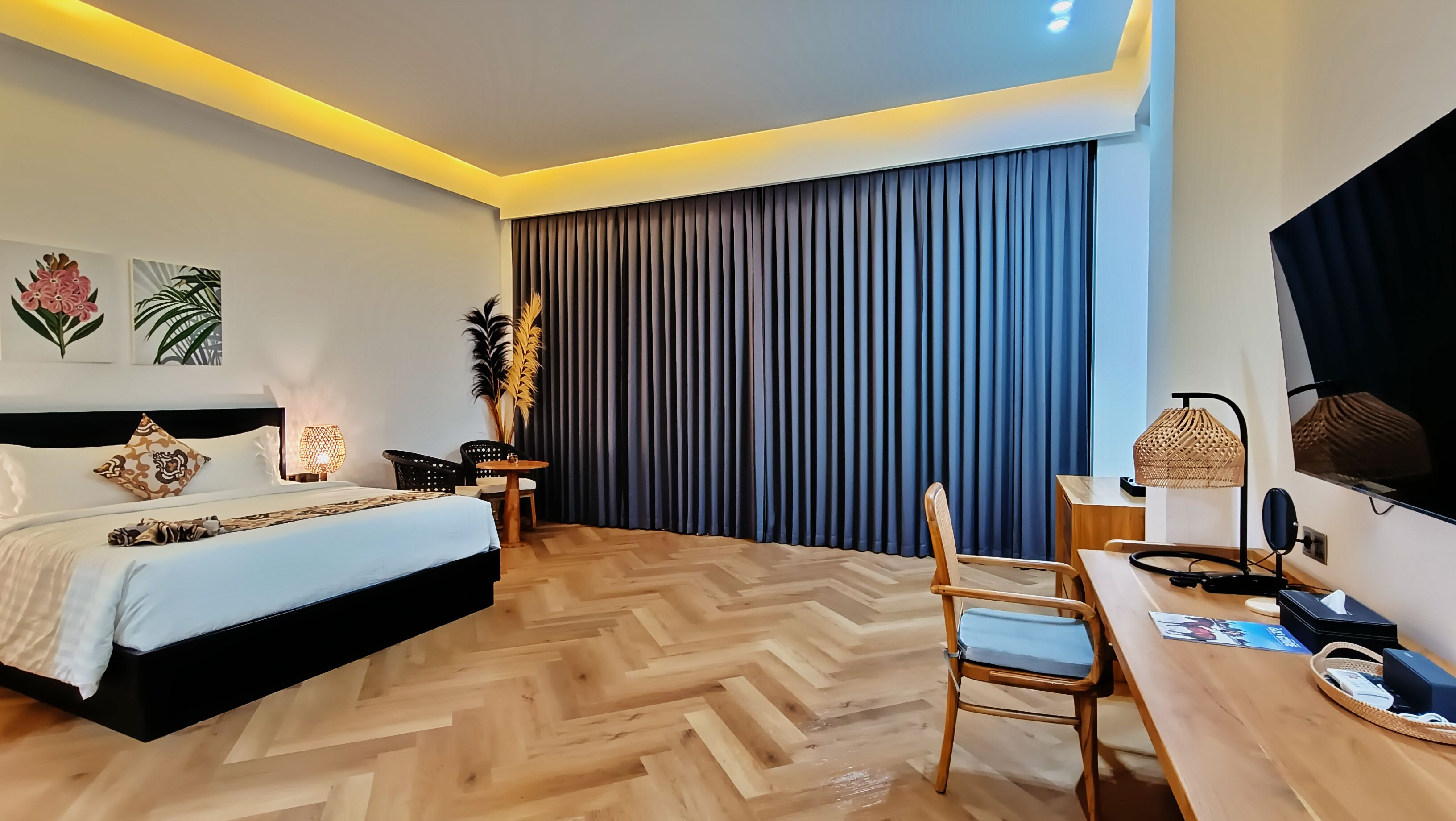 A modern hotel room with a large bed, a desk, and a television.