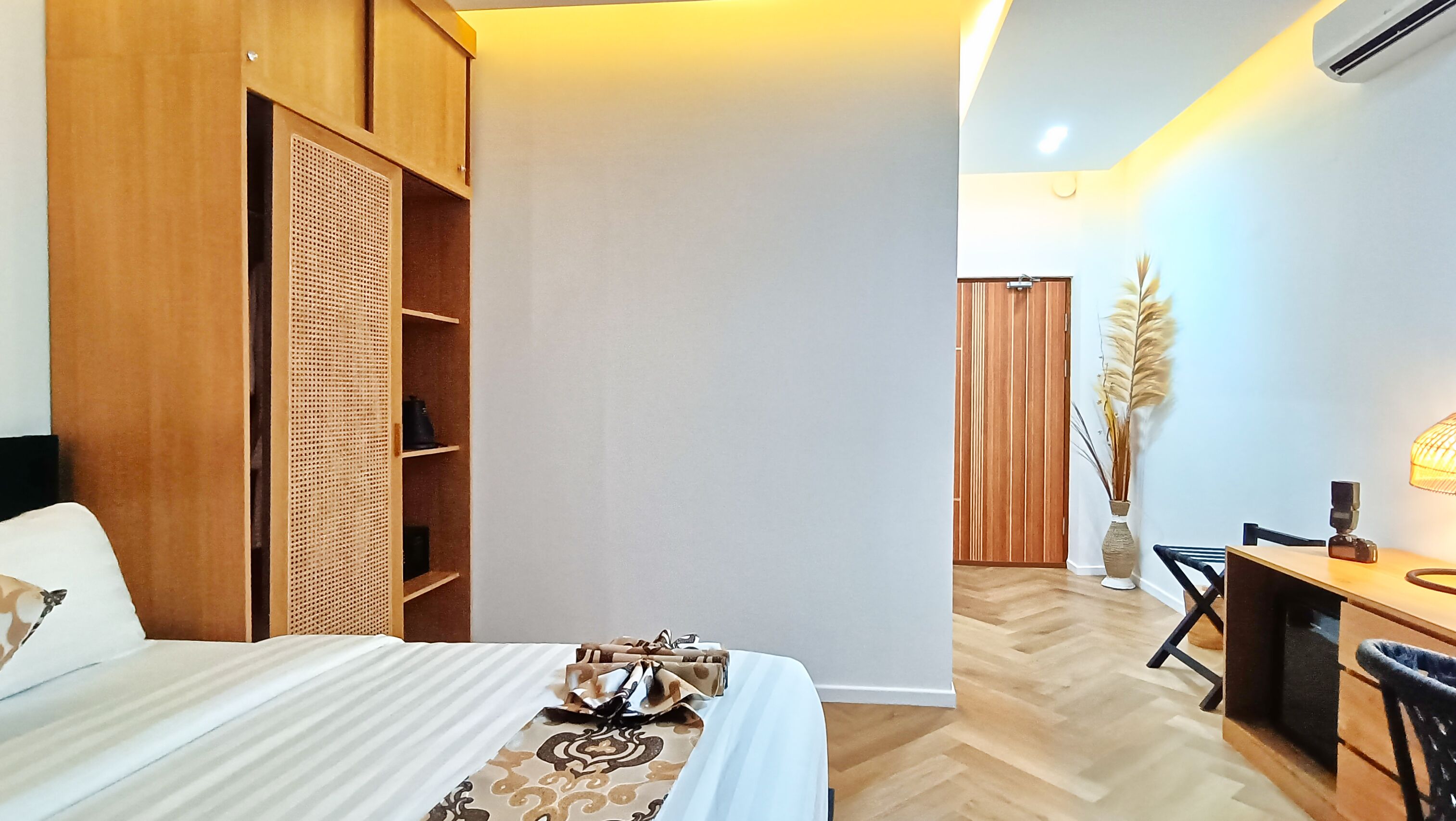 Un dormitorio con cama, armario de madera, escritorio con silla y lámpara.