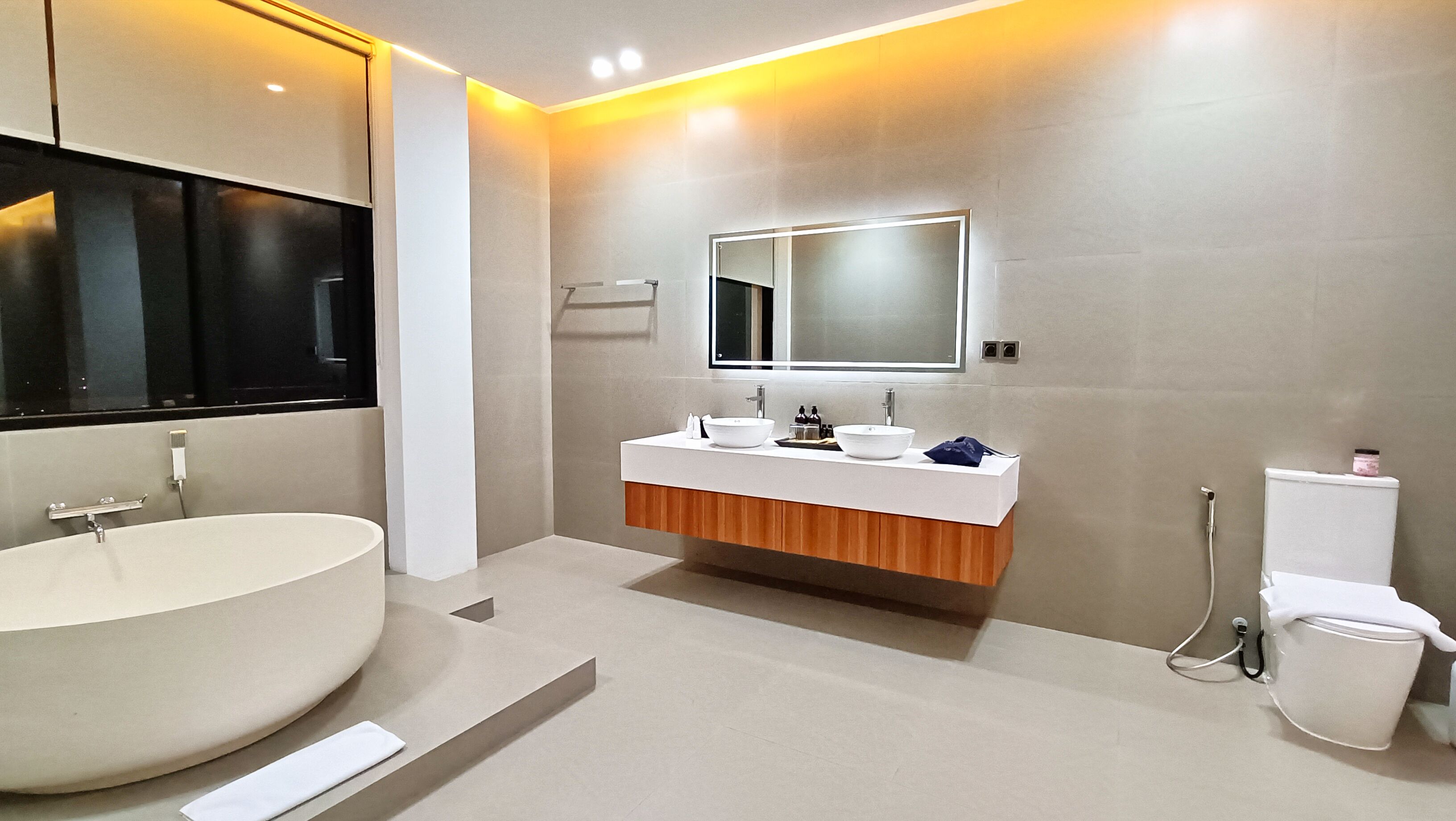 A modern bathroom with a freestanding bathtub, a vanity with two sinks, and a toilet.