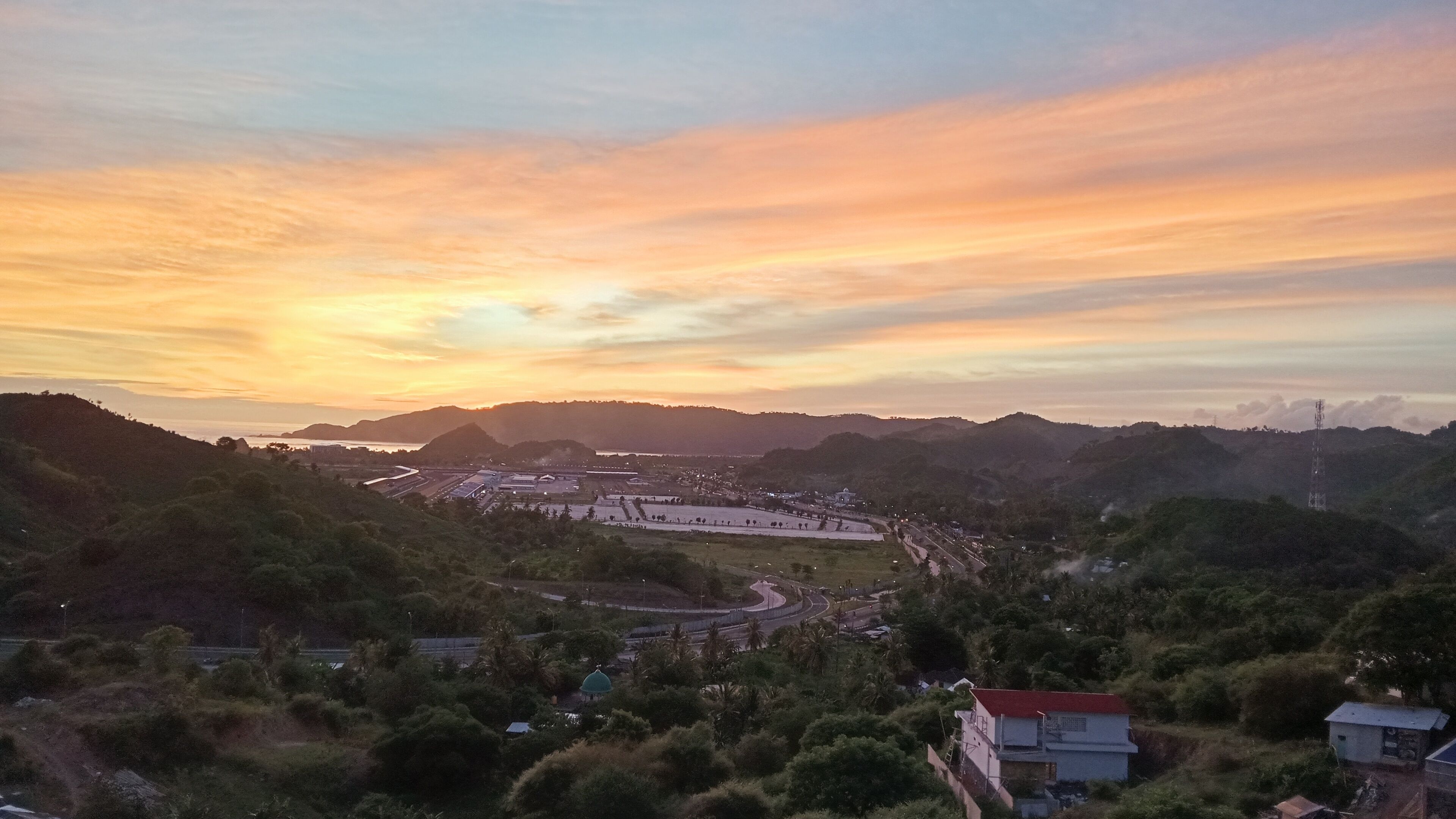 A landscape with a winding road, buildings, and hills.