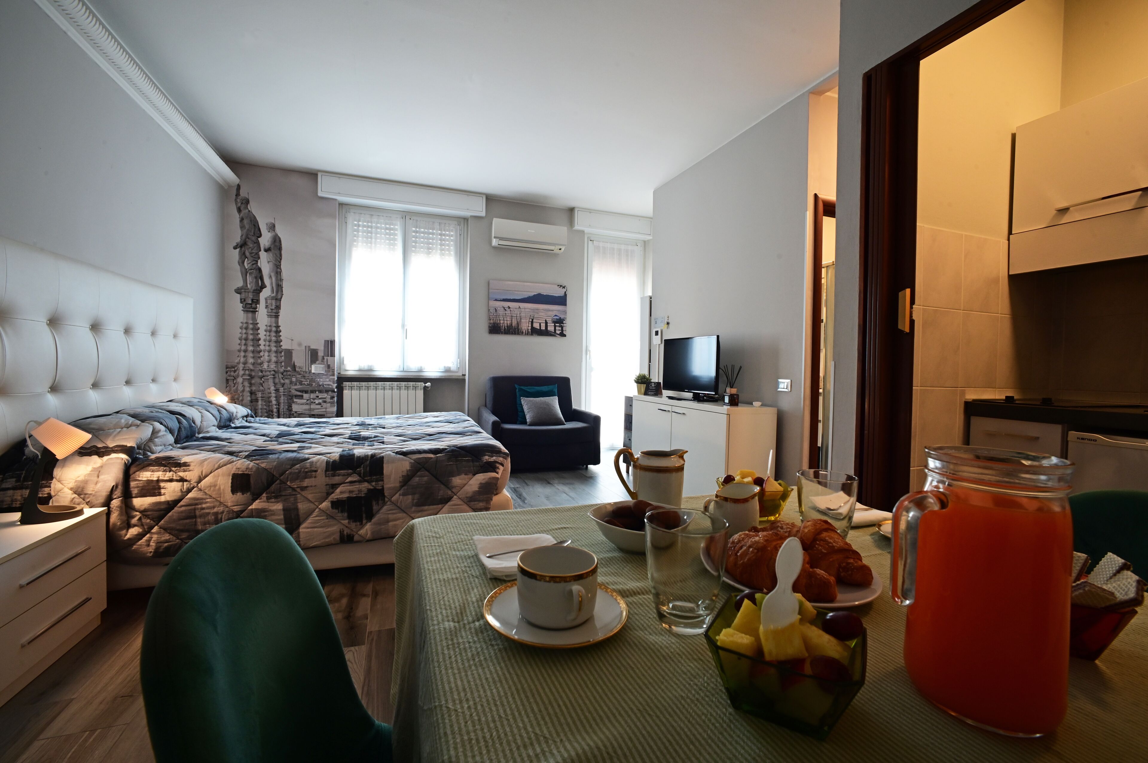 Une chambre d’hôtel avec un lit, une table à manger dressée pour le petit-déjeuner, une télévision et une cheminée.